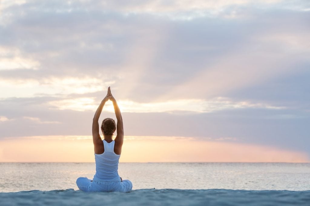 A woman practicing yoga at the seashore