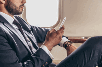 A business man using his phone while sat on a plane
